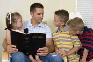 A father reads to his children from the Bible.